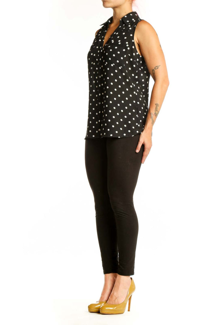 Black sleeveless button-up blouse with white polka dot pattern, front view