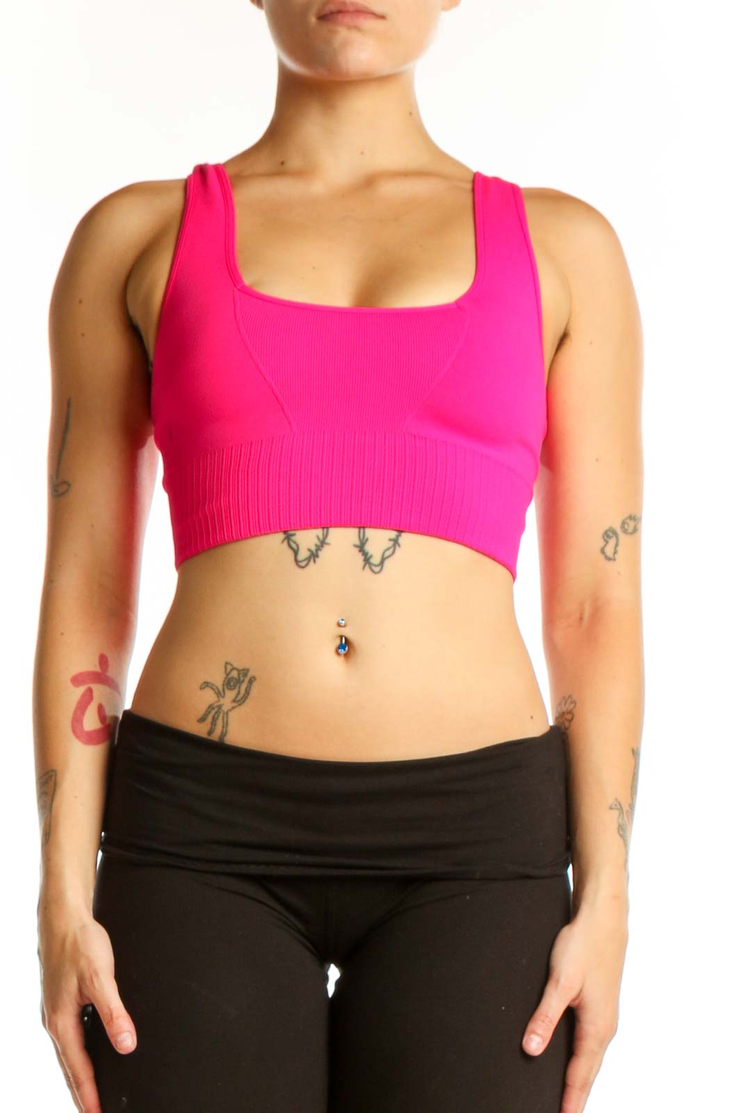 Front view of pink ribbed sports bra with scoop neckline and racerback support, paired with black leggings