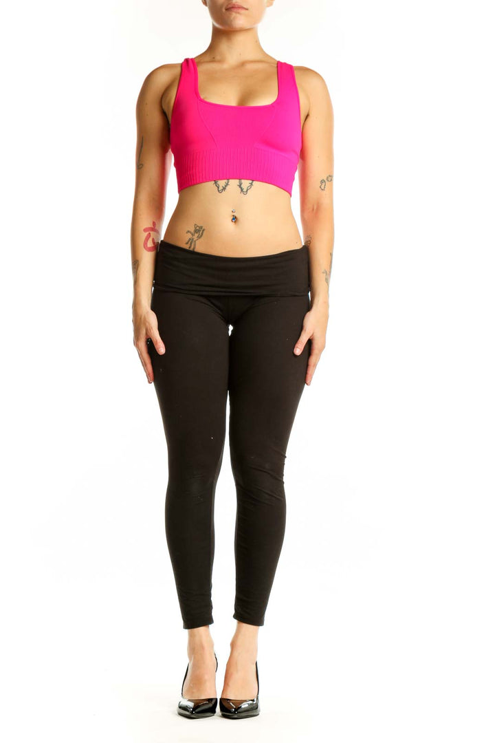 Front view of pink ribbed sports bra with scoop neckline and racerback support, paired with black leggings