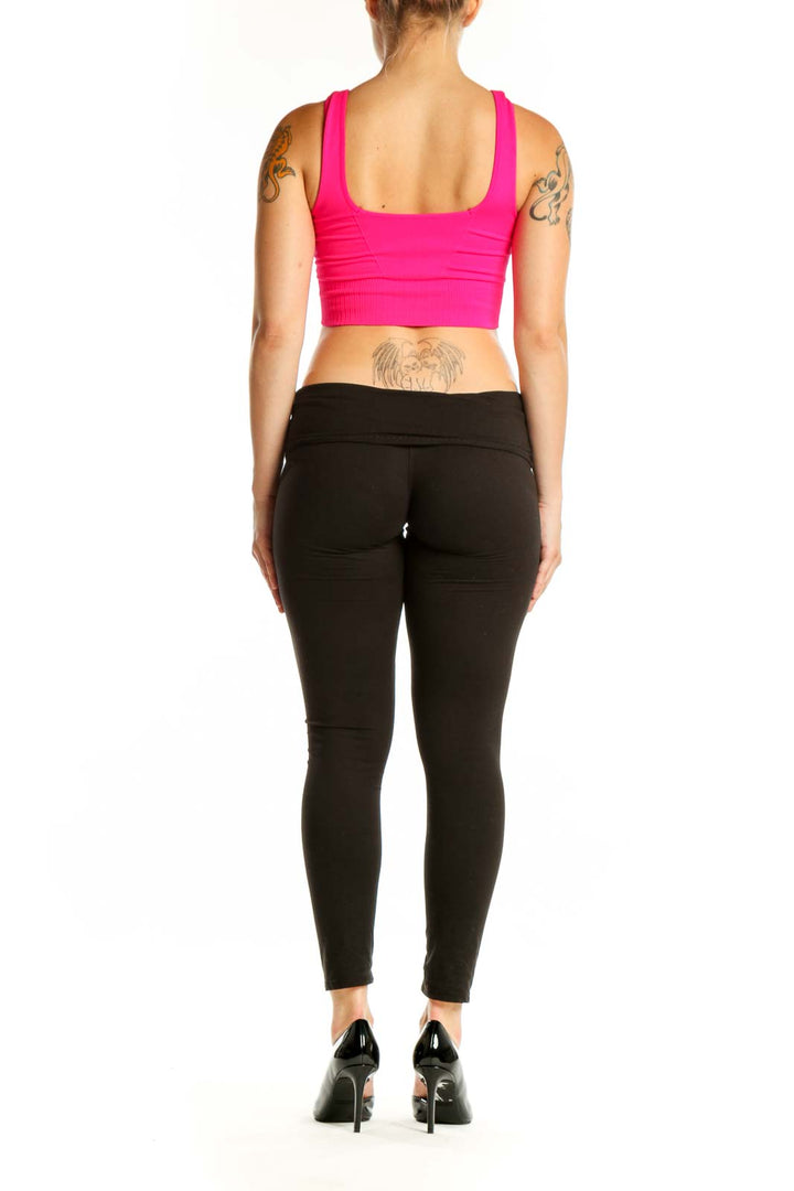 Back view of pink ribbed sports bra showing supportive racerback design and fit on black leggings
