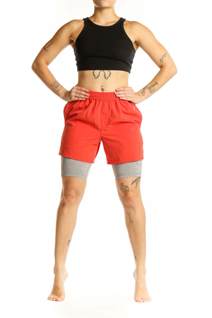 Red athletic shorts with gray compression liners, front view showing elastic waistband and functional pockets