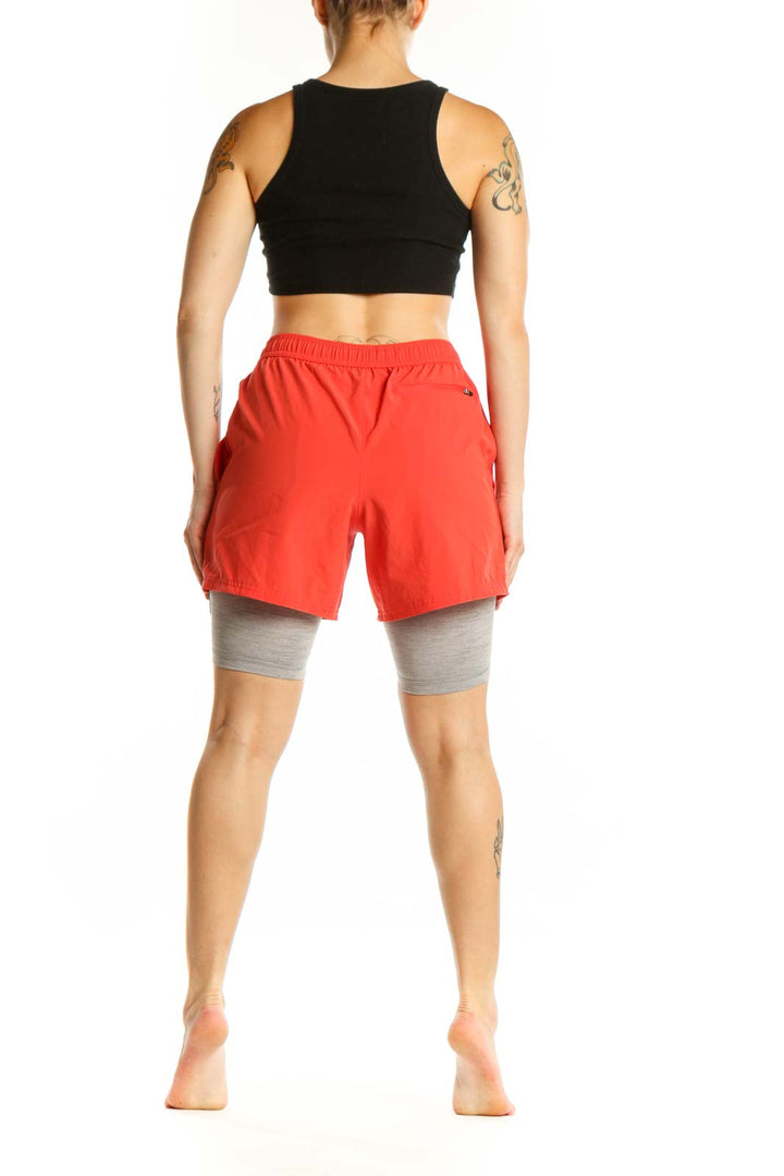 Red athletic shorts with gray compression liners, back view displaying relaxed fit and mid-thigh length