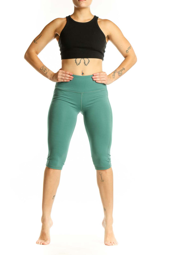 Woman wearing sage green high-waist capri leggings with black sports bra, front view
