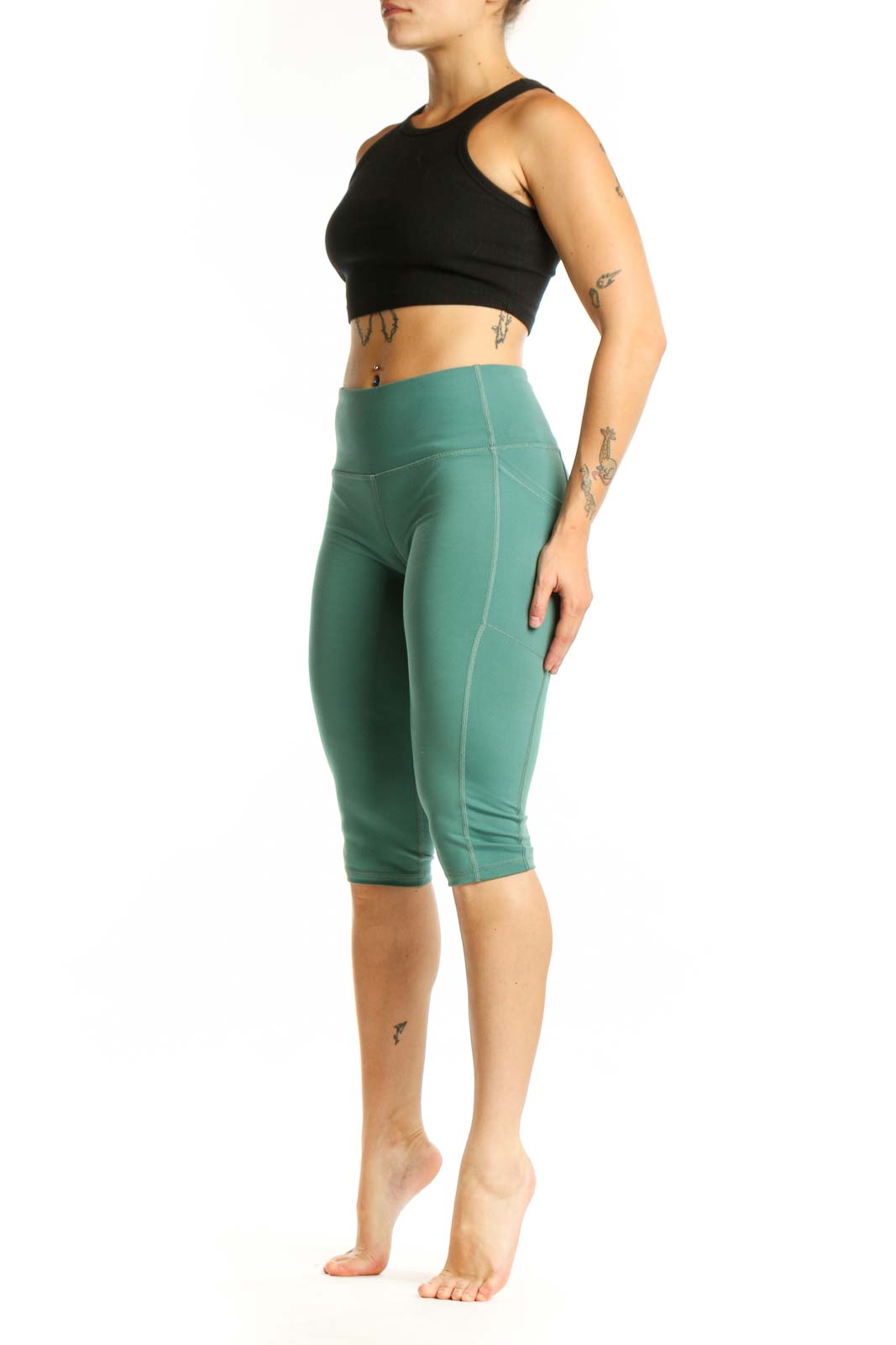 Woman wearing sage green high-waist capri leggings with black sports bra, front view