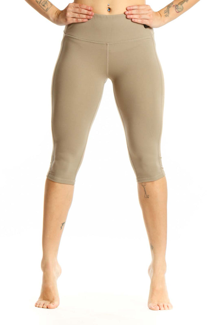 Woman wearing beige high-waist capri leggings with side pockets, front view