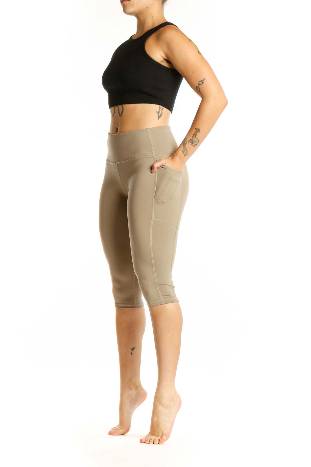 Woman wearing beige high-waist capri leggings with side pockets, front view
