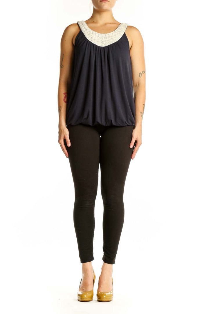 Navy sleeveless tank top with cream embellished beaded neckline and gathered front, worn with black pants