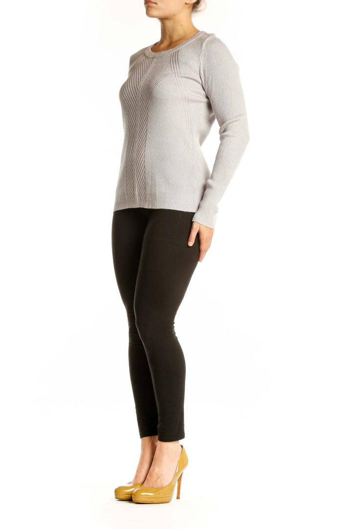 Cream ribbed knit sweater with metallic threading, crew neckline, and long sleeves on model wearing black pants