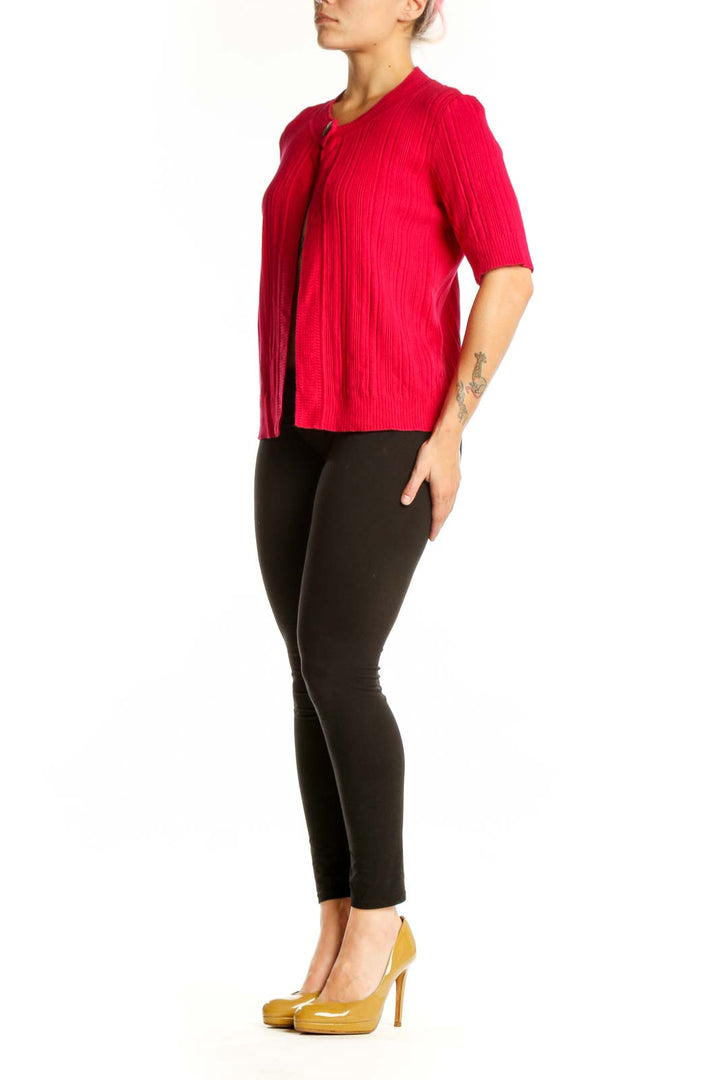 Red ribbed knit cardigan with button-front closure and three-quarter sleeves, worn open over black pants