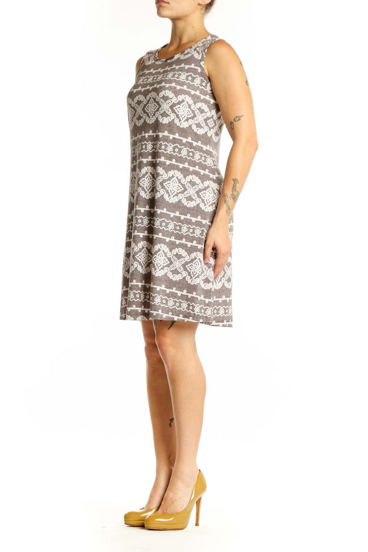 Front view of taupe geometric print A-line dress with cream and white diamond motifs, sleeveless crew neckline design