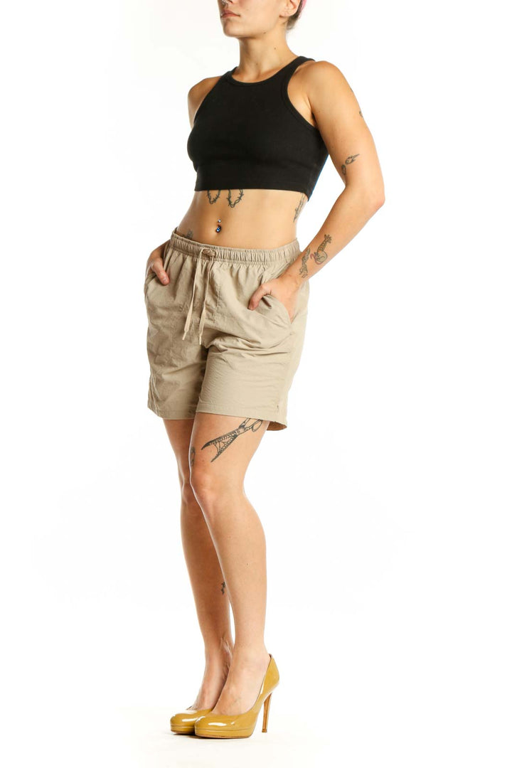 Beige DSG athletic shorts with elastic waistband and drawstring, front view on model