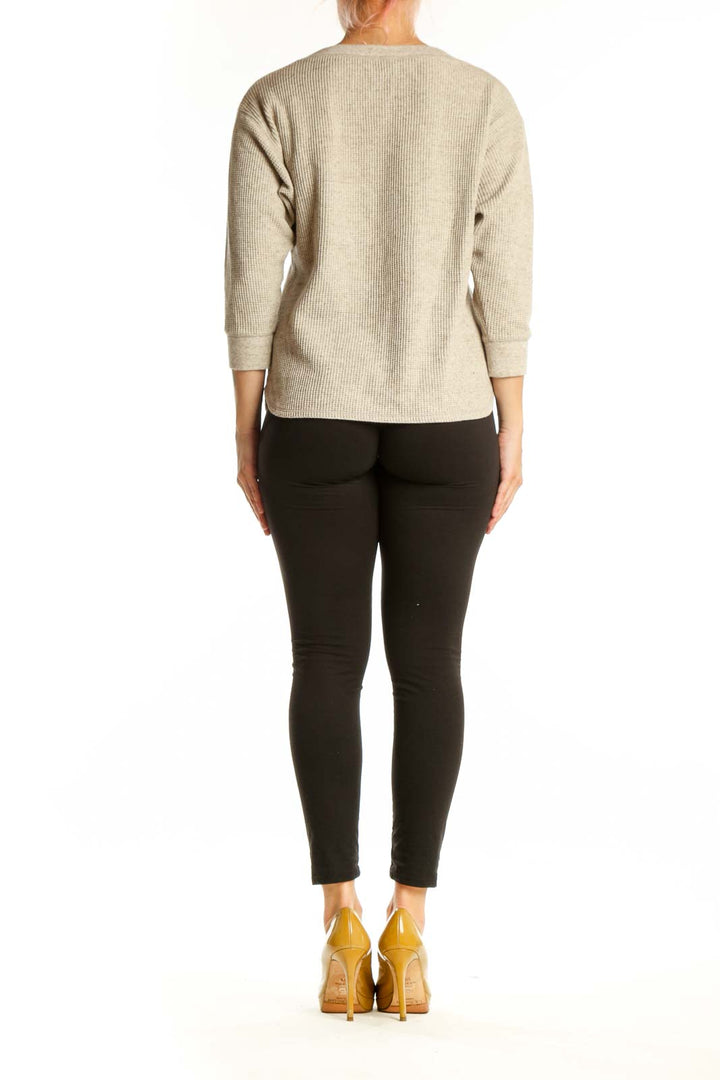 Beige ribbed cotton knit sweater back view showing relaxed fit and curved hem