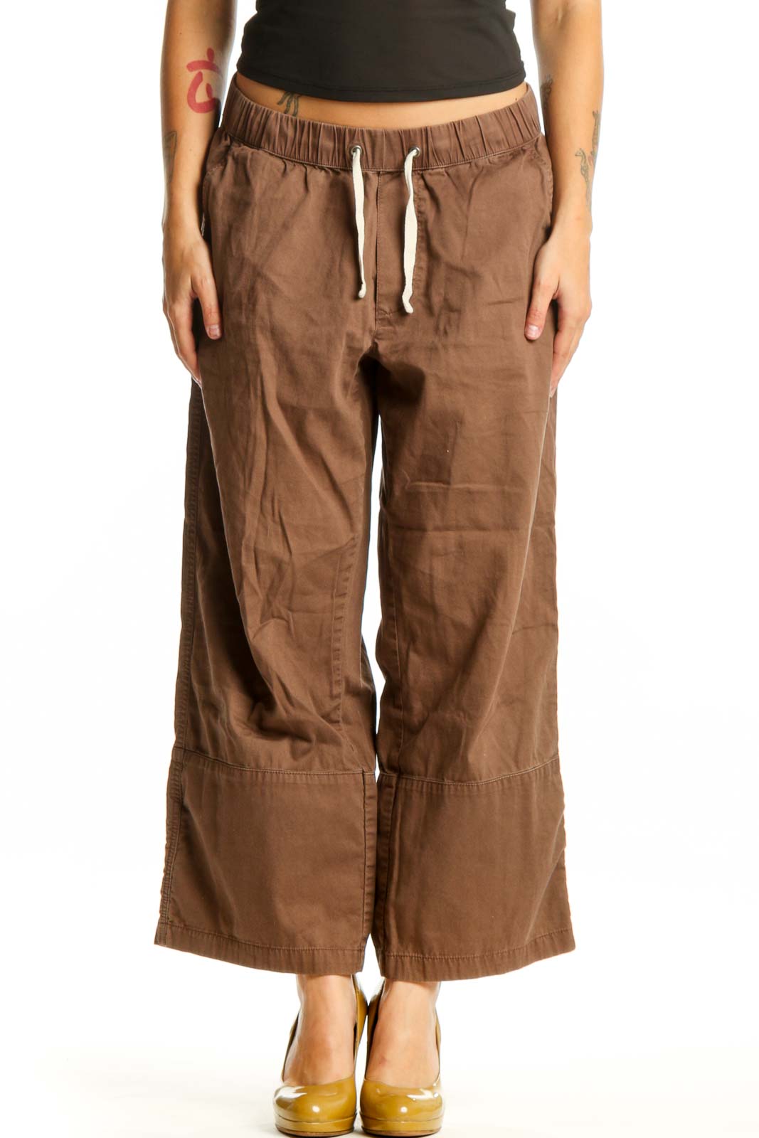 Brown organic cotton drawstring pants with relaxed fit and front pockets, shown on model from front view