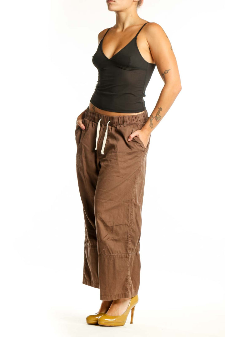 Brown organic cotton drawstring pants with relaxed fit and front pockets, shown on model from front view