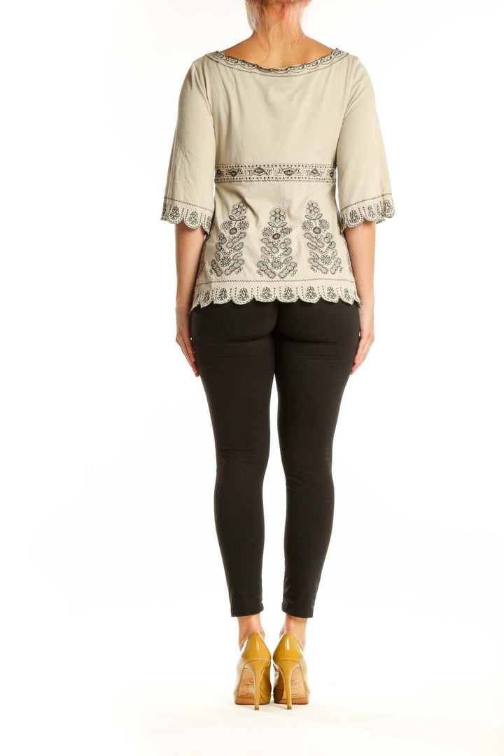 Back view of cream embroidered cotton top showing empire waist and scalloped hem detail