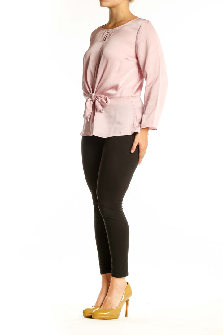 Pink tie-front long sleeve blouse with crew neckline, front view on model