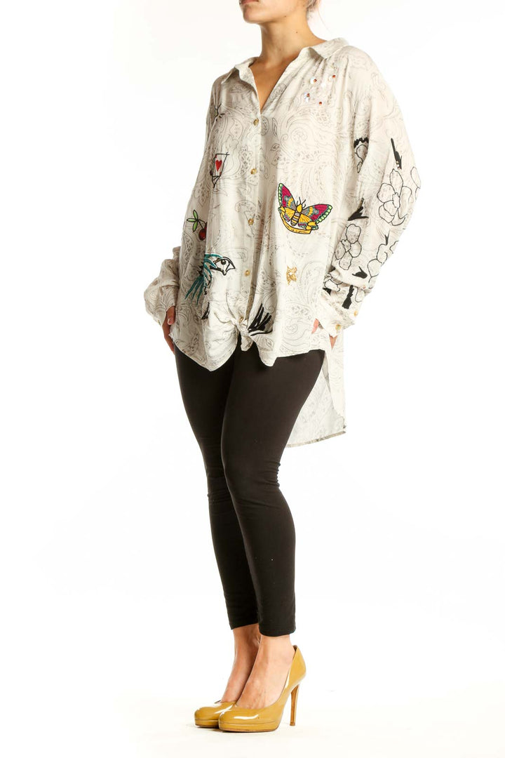 Cream Pilcro rayon shirt with whimsical embroidered birds, butterflies, hearts, and line drawings on front, worn with black leggings