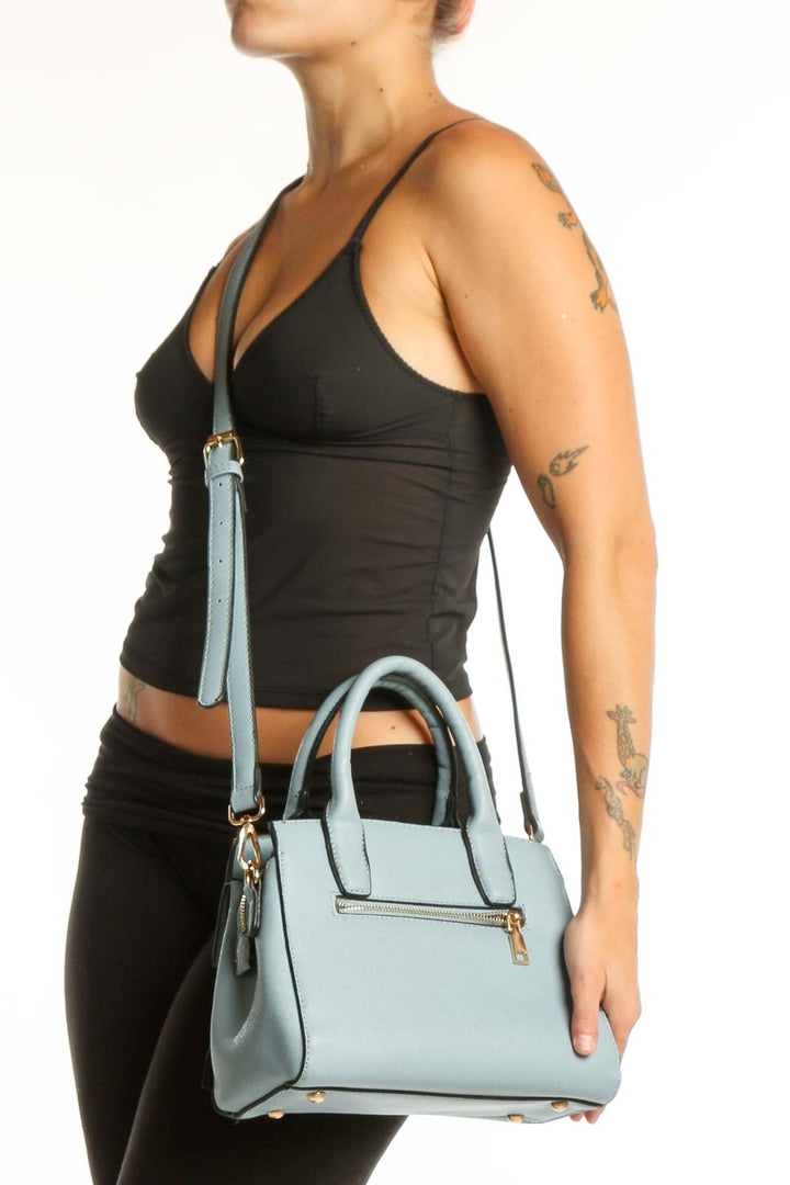 Light blue SilkRoll shoulder bag with dual handles and adjustable crossbody strap, displayed with gold-tone hardware and front zip pocket