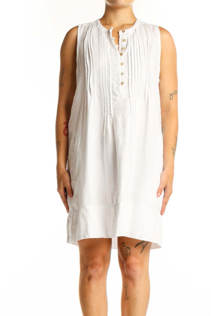 White linen sleeveless button-front dress with vertical pleating and henley neckline, front view