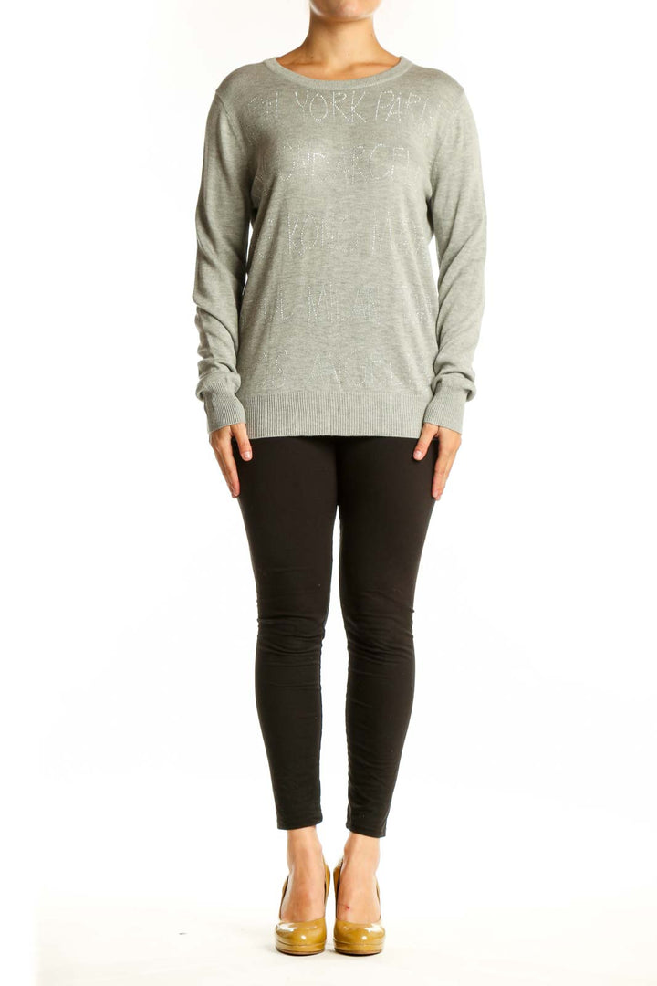 Beige cashmere blend knit pullover with embellished text detail, crew neckline, and long sleeves on model