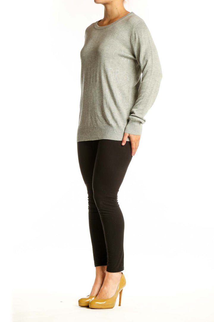 Beige cashmere blend knit pullover with embellished text detail, crew neckline, and long sleeves on model