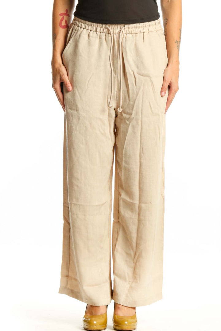 Cream wide leg drawstring pants with relaxed fit and side pockets, front view