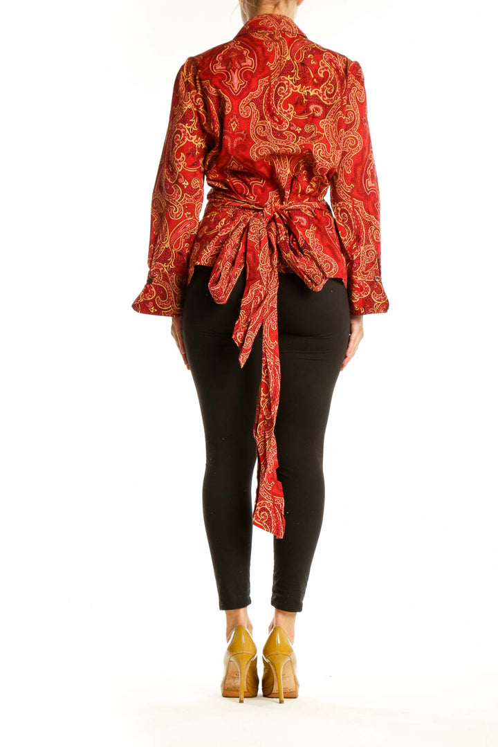 Red and gold paisley print button-up blouse with long sleeves, back view with tie detail