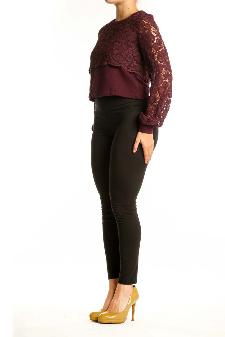 Burgundy lace cropped knit top with long voluminous sleeves and solid panel, styled with black pants