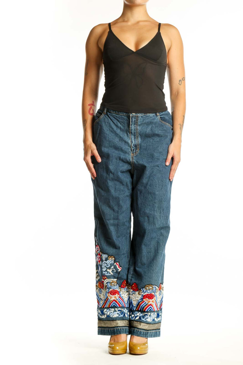 Front view of blue embroidered denim jeans with colorful floral and ornamental design at hem by Chico's Design