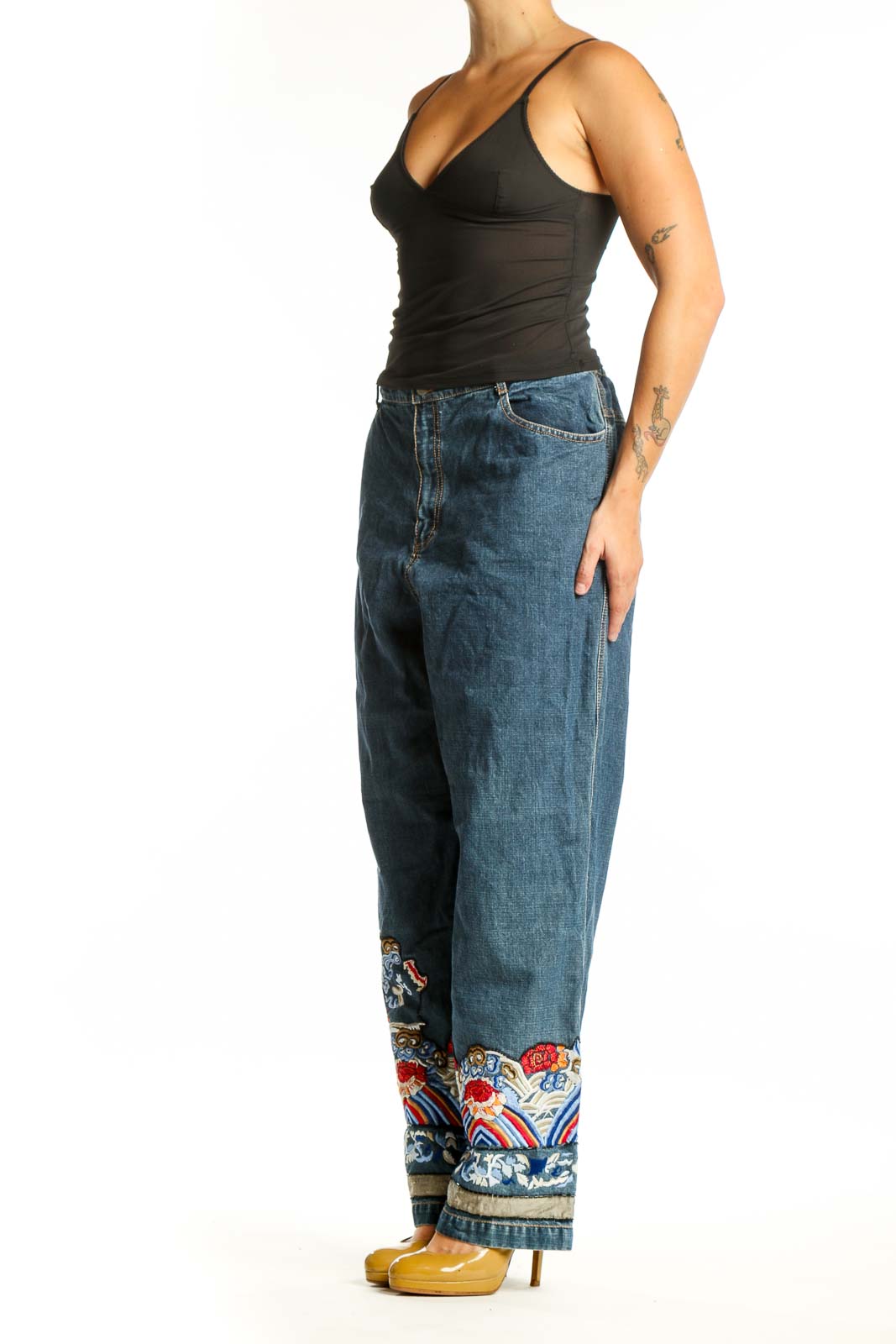 Front view of blue embroidered denim jeans with colorful floral and ornamental design at hem by Chico's Design