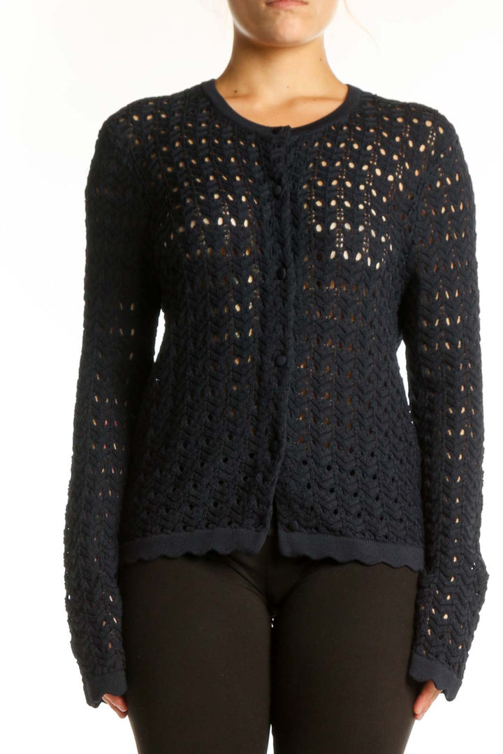 Black openwork knit cardigan with button-front closure and long sleeves, worn with black pants