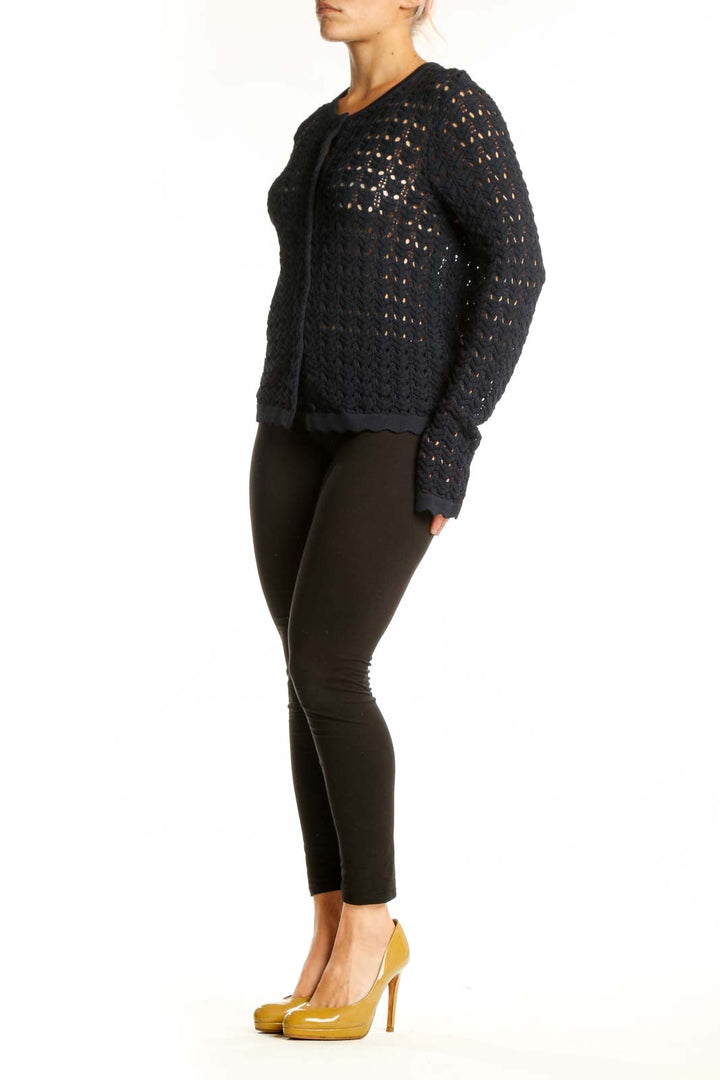 Black openwork knit cardigan with button-front closure and long sleeves, worn with black pants