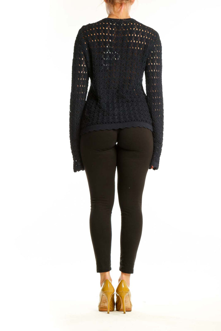 Back view of black openwork knit cardigan showing intricate eyelet pattern and fitted silhouette