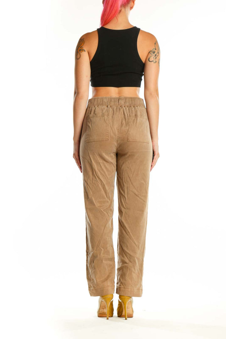 Beige cargo pants with rolled cuffs and side pockets, back view on model