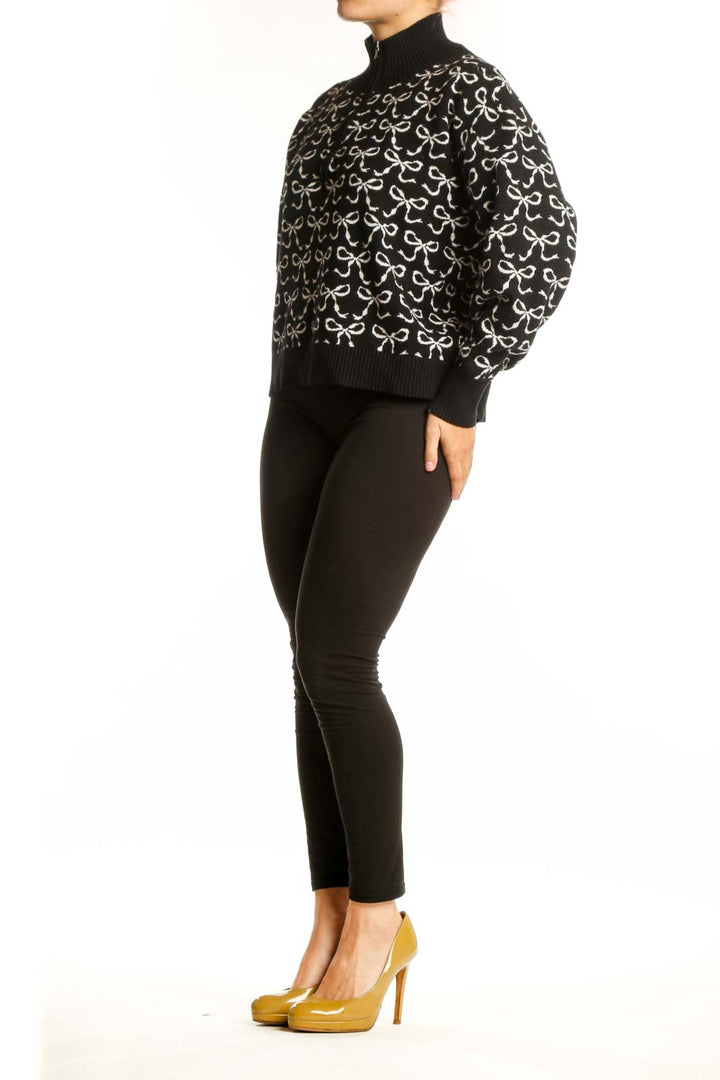 Black pullover knit with cream bow print pattern, half-zip neckline, and ribbed collar by Maeve
