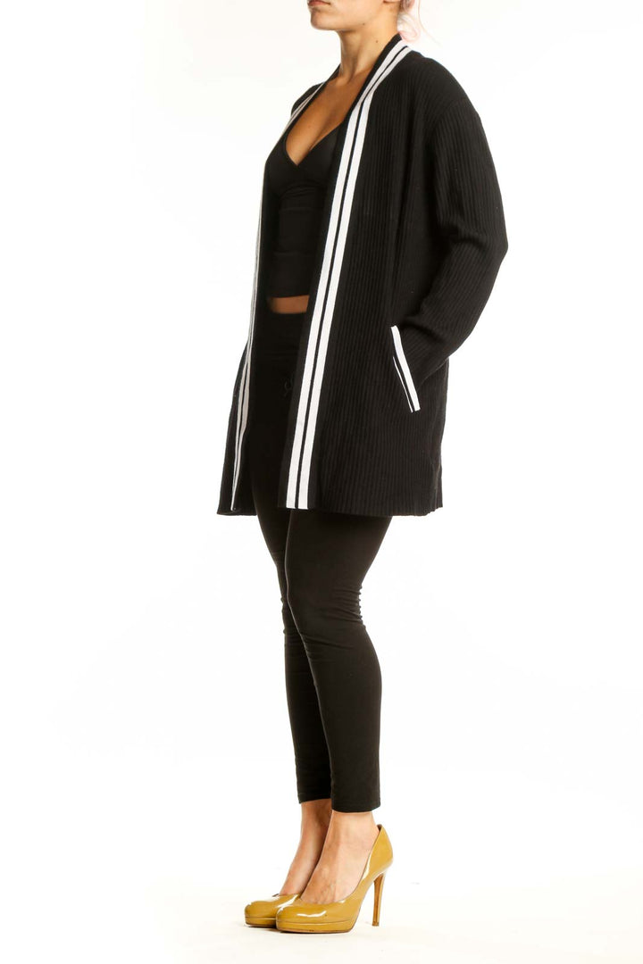 Black ribbed cardigan with white stripe trim worn open over black crop top, front view