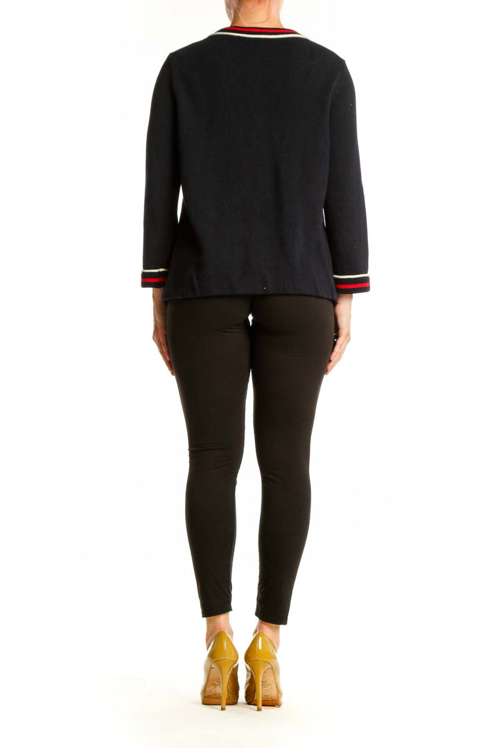 Black cotton cardigan with striped trim, back view showing zip closure and overall silhouette