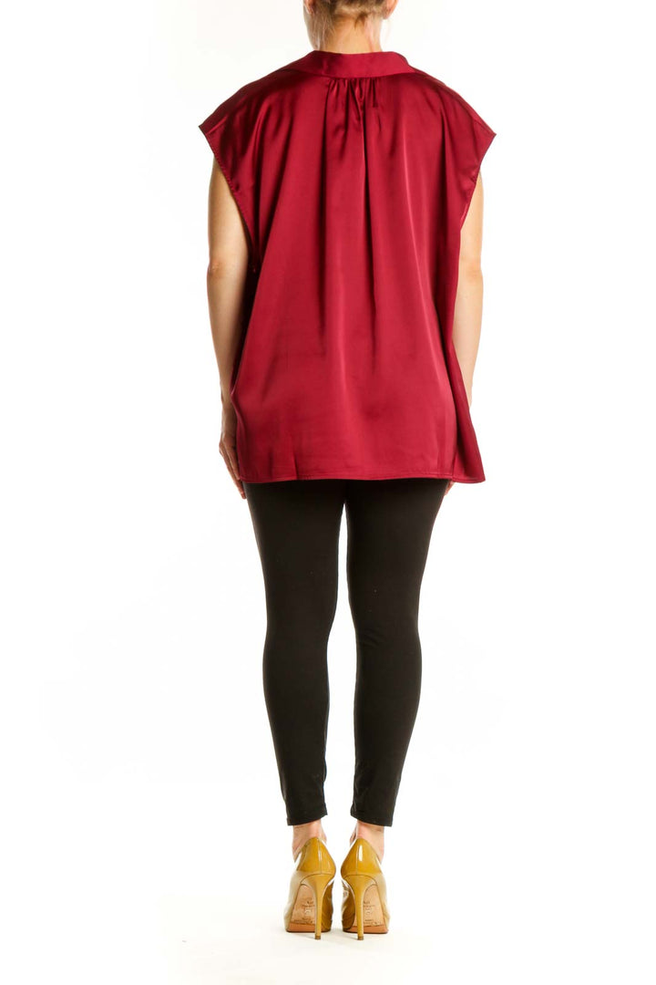 Burgundy button-up cap sleeve blouse, back view on model wearing black leggings