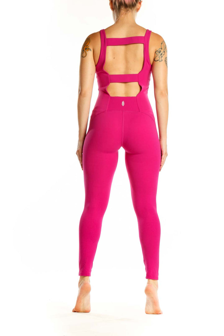 Back view of hot pink Free People jumpsuit showing sleeveless design and fitted waist with tapered leg detail