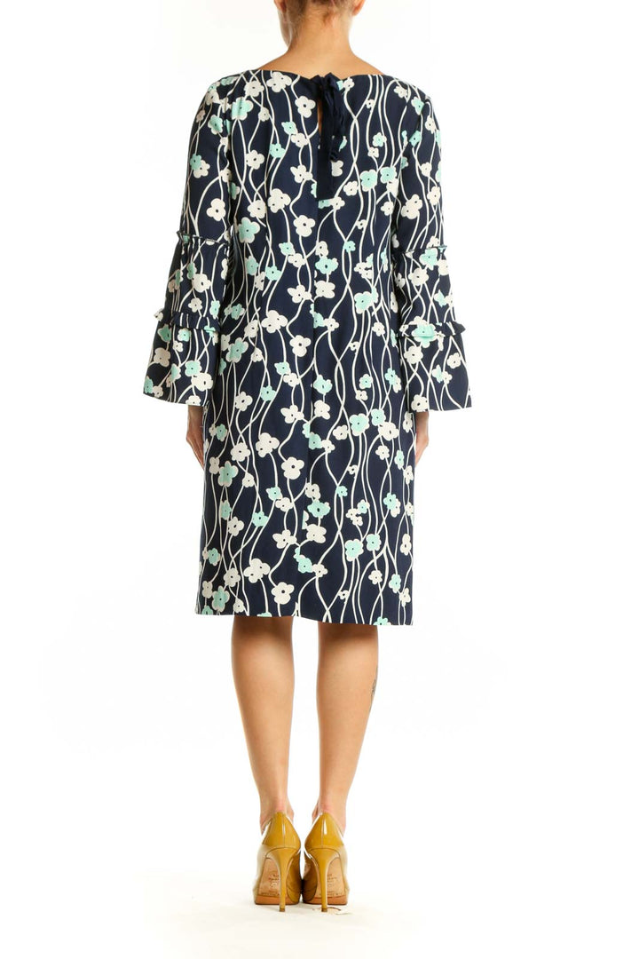 Navy floral canvas dress with bell sleeves, back view on model wearing yellow heels