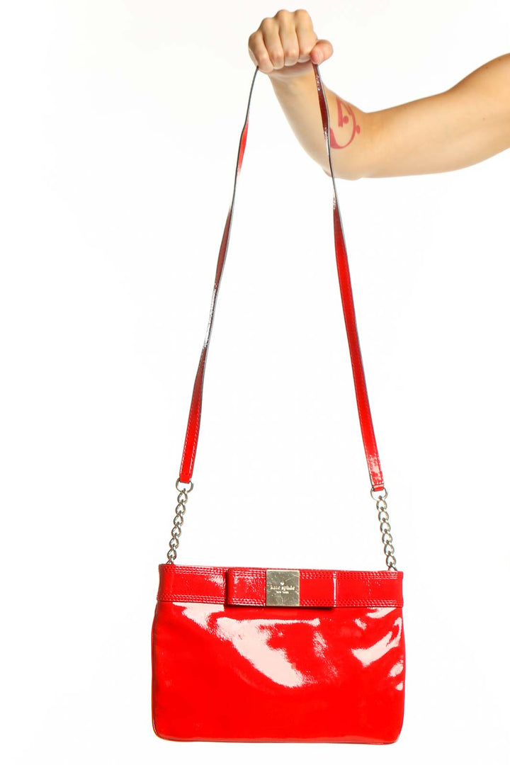 Kate Spade Red Patent Leather Crossbody Bag with bow detail and chain straps held in hand