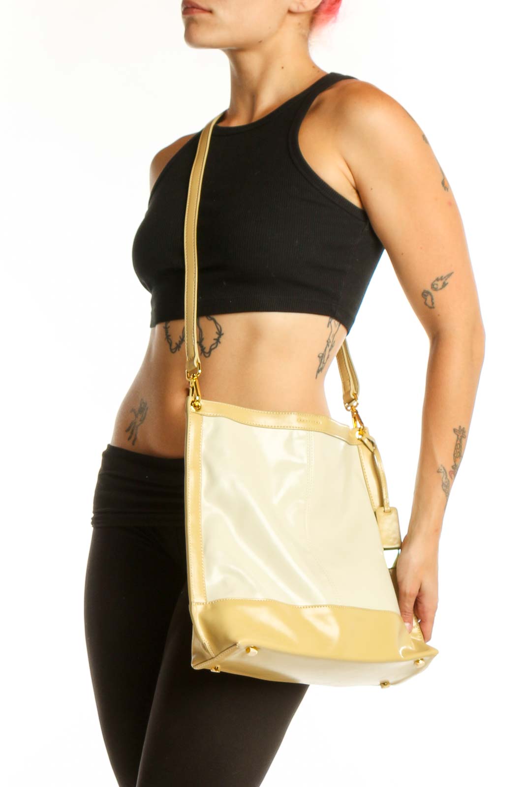 SilkRoll gold and cream leather crossbody bag with adjustable strap held in hand, showing front view with color-block design