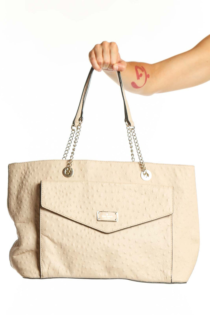 Cream quilted Kate Spade shoulder tote with chain-accented straps and envelope flap closure, held by hand