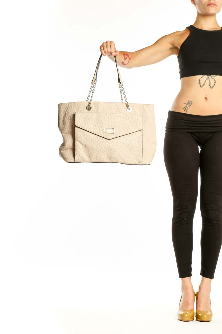 Cream quilted Kate Spade shoulder tote with chain-accented straps and envelope flap closure, held by hand