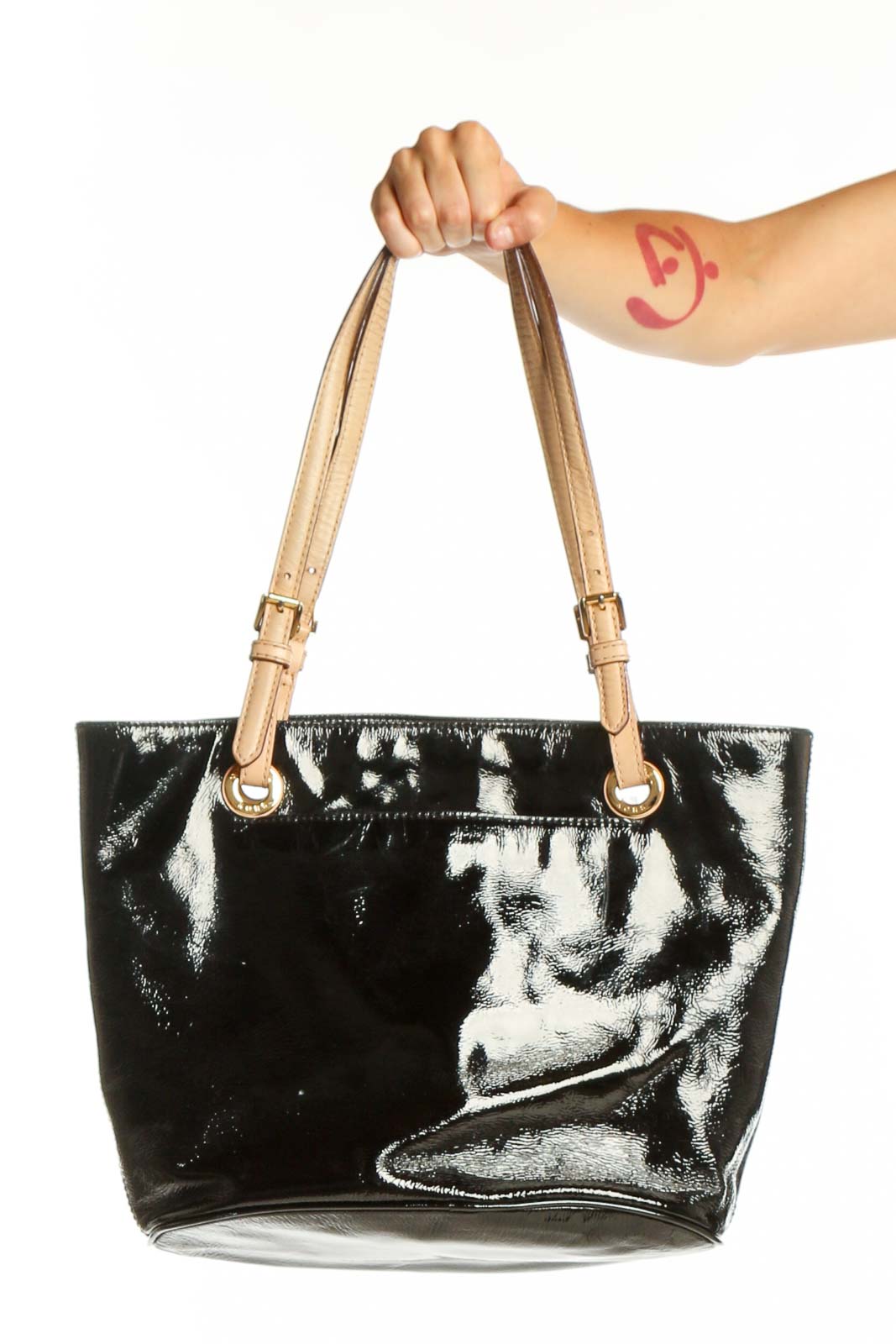 Black patent leather Michael Kors tote bag with tan handles held by model, front view