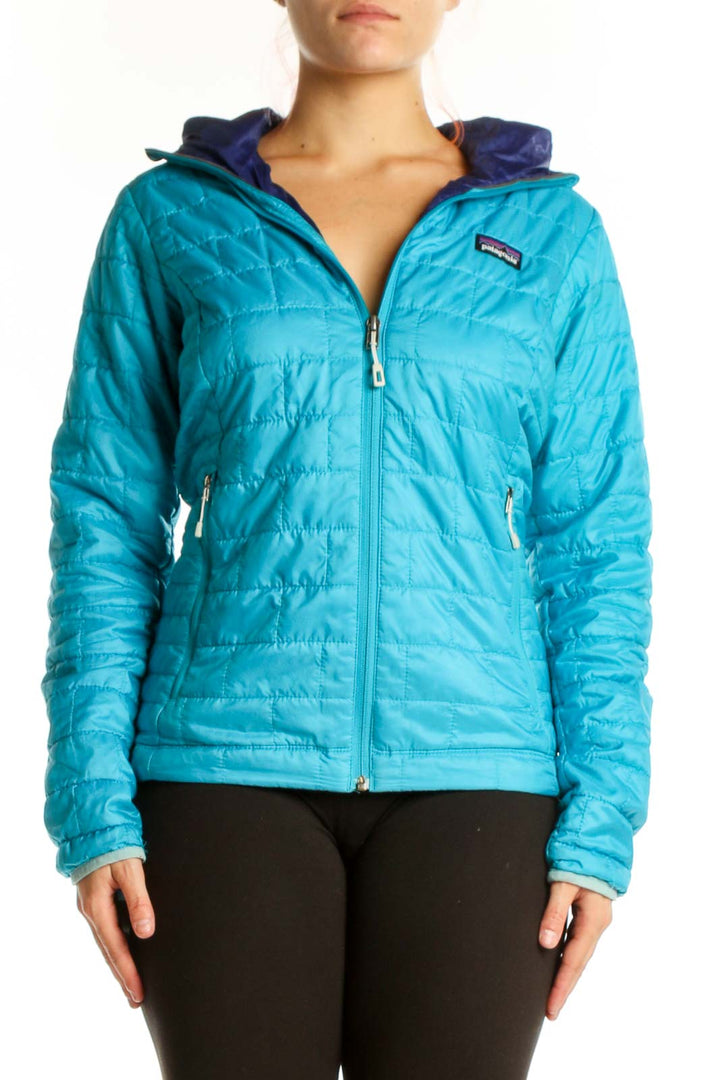 Woman wearing turquoise quilted Patagonia puffer jacket with navy hood lining, front view