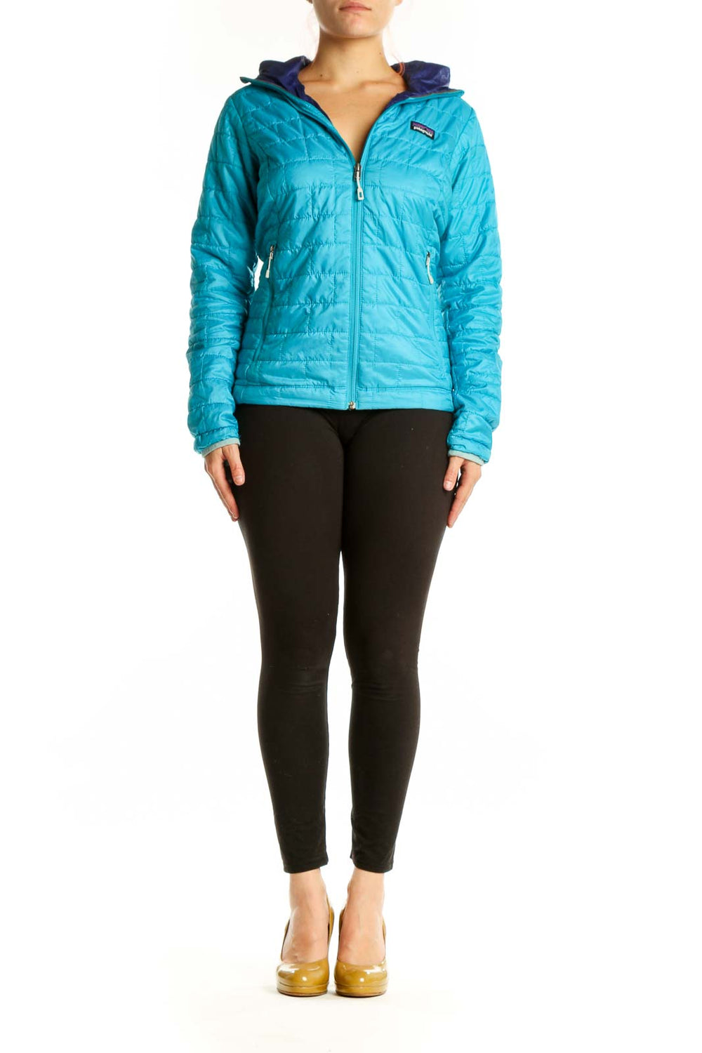Woman wearing turquoise quilted Patagonia puffer jacket with navy hood lining, front view