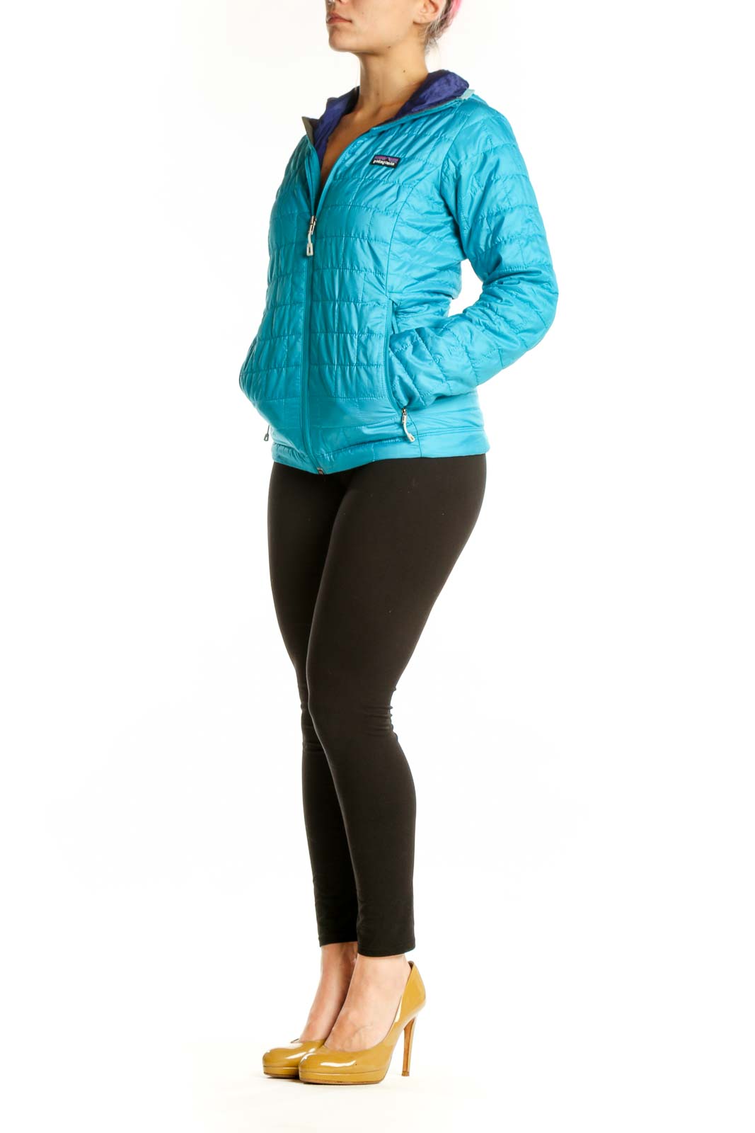 Woman wearing turquoise quilted Patagonia puffer jacket with navy hood lining, front view