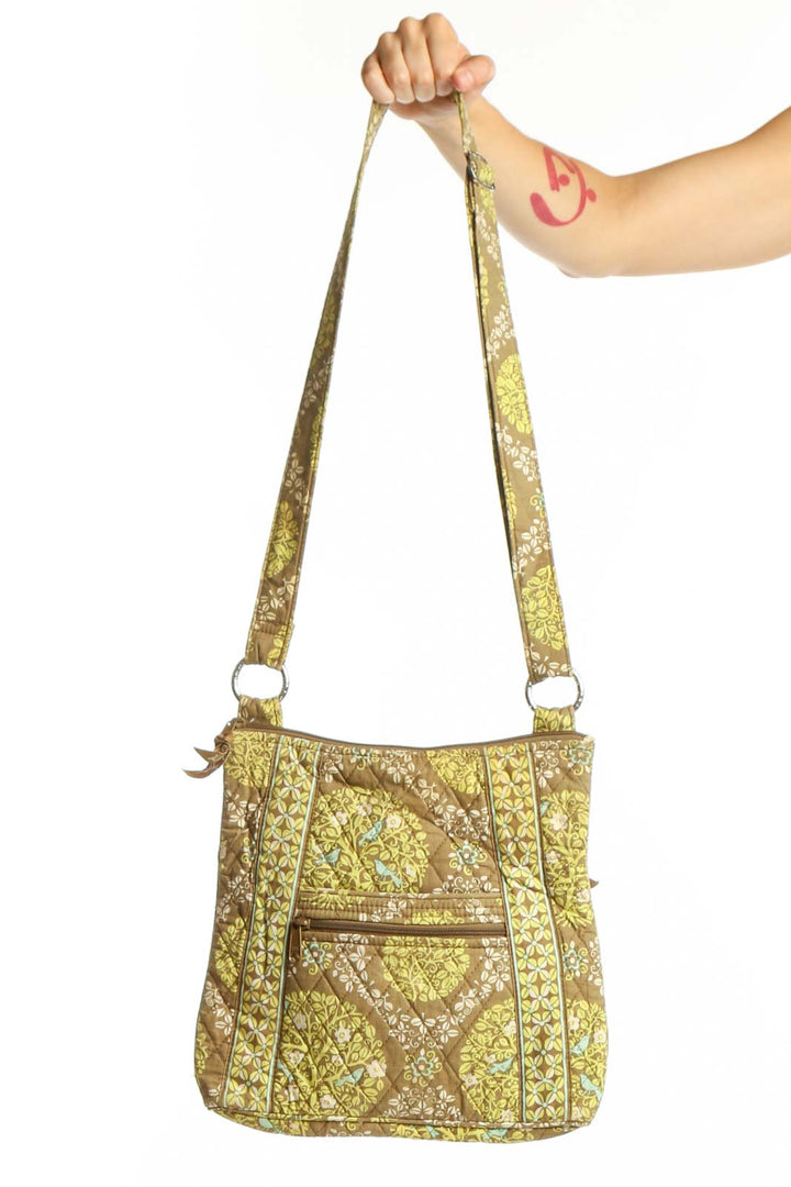 Yellow quilted Vera Bradley crossbody bag with geometric pattern and adjustable fabric straps held in hand
