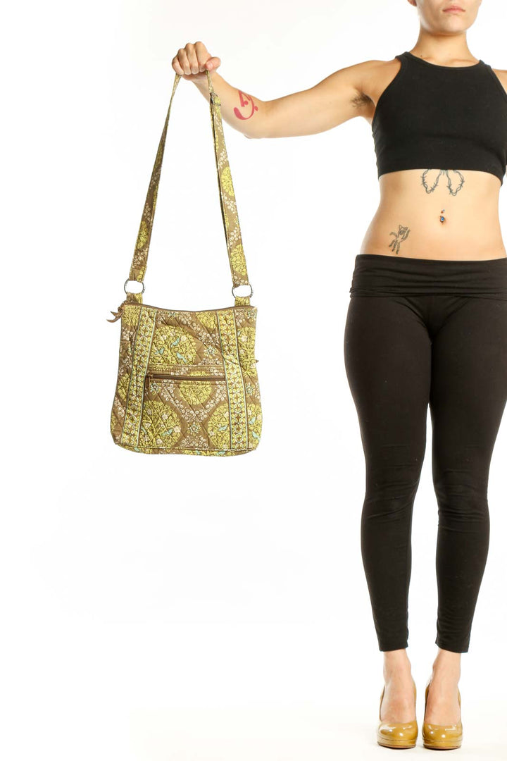 Yellow quilted Vera Bradley crossbody bag with geometric pattern and adjustable fabric straps held in hand